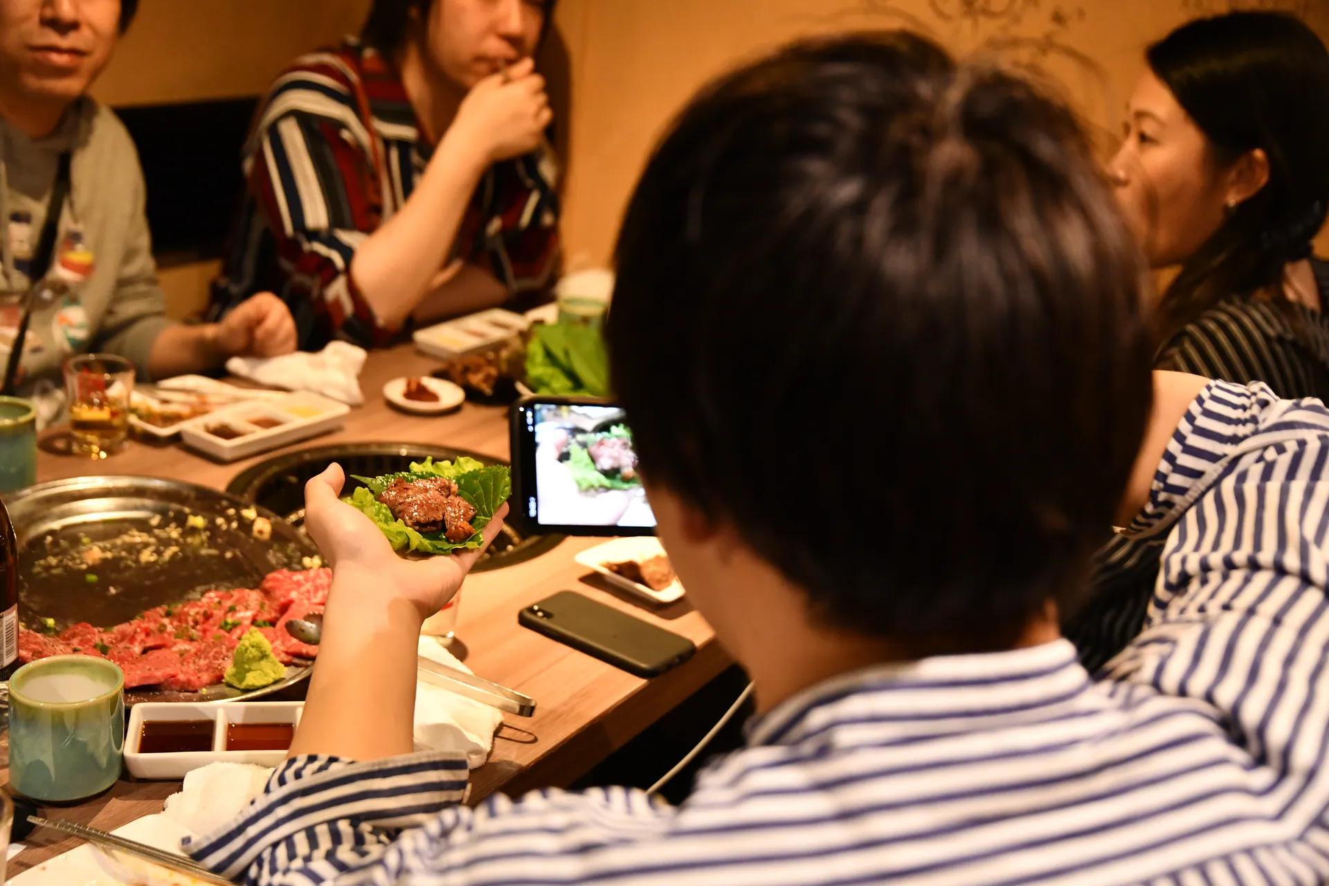 サンチュに乗せた肉を撮る人